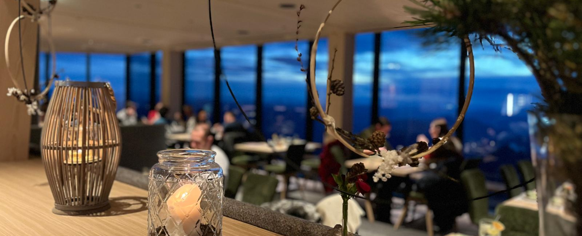 Kerzendekoration im Glas vor Fenster mit Blick auf den Dachstein bei abendlicher Adventstimmung | © Planai-Hochwurzen-Bahnen