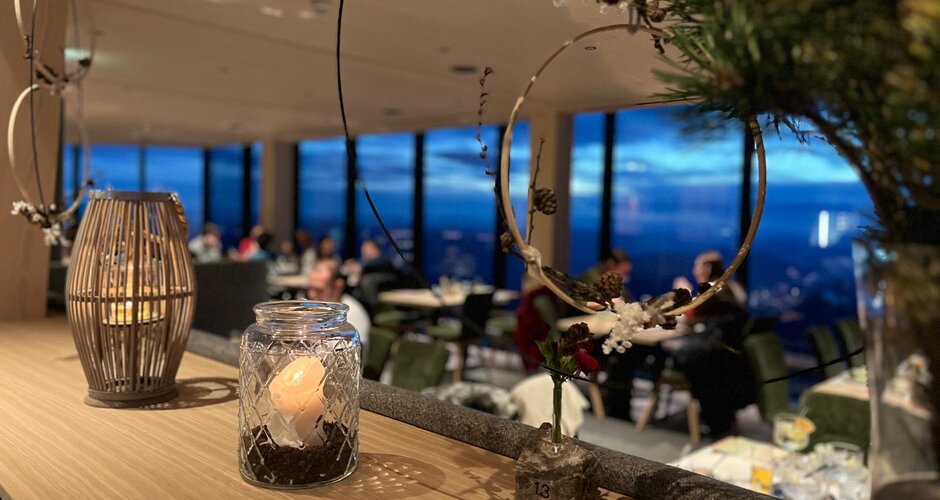 Kerzendekoration im Glas vor Fenster mit Blick auf den Dachstein bei abendlicher Adventstimmung | © Planai-Hochwurzen-Bahnen