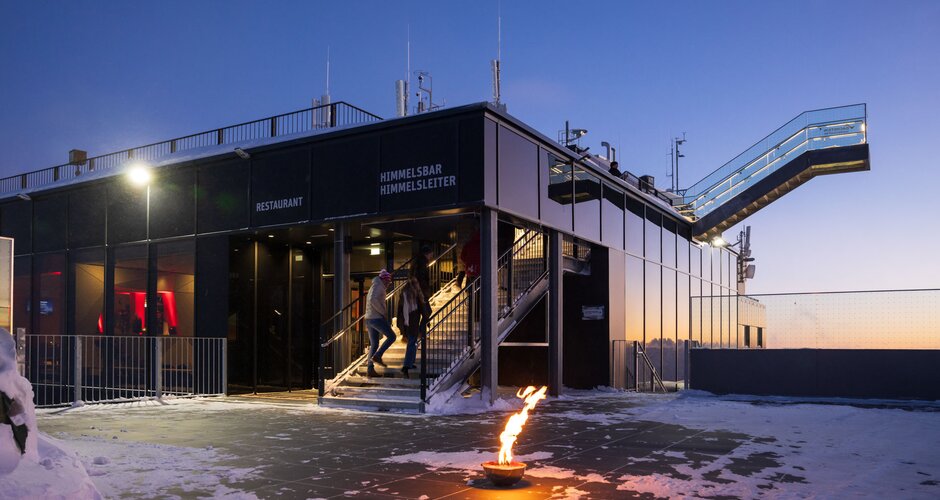Modernes Gebäude am Dachstein mit Flamme und Himmelsleiter bei Sonnenuntergang im Schnee | © Martin Huber