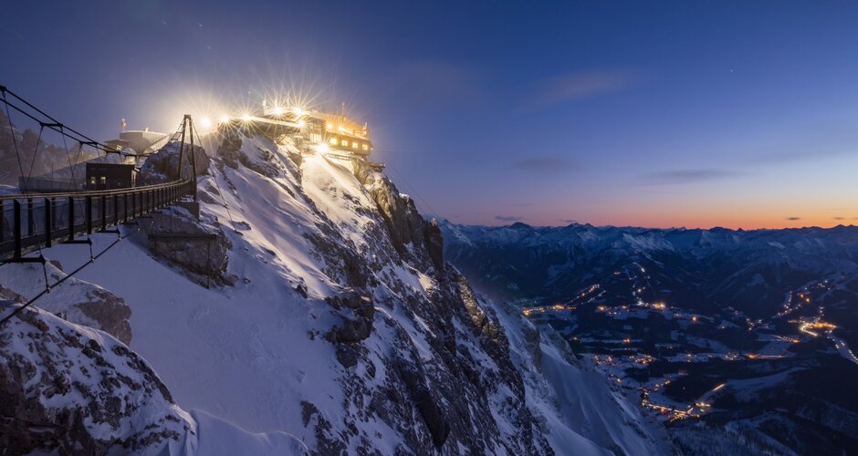 Beleuchtete Bergstation mit Hängebrücke am Dachstein bei Dämmerung mit Blick ins Tal | © Martin Huber