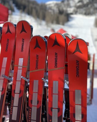 Red Atomic ski pairs leaning against a ski rack