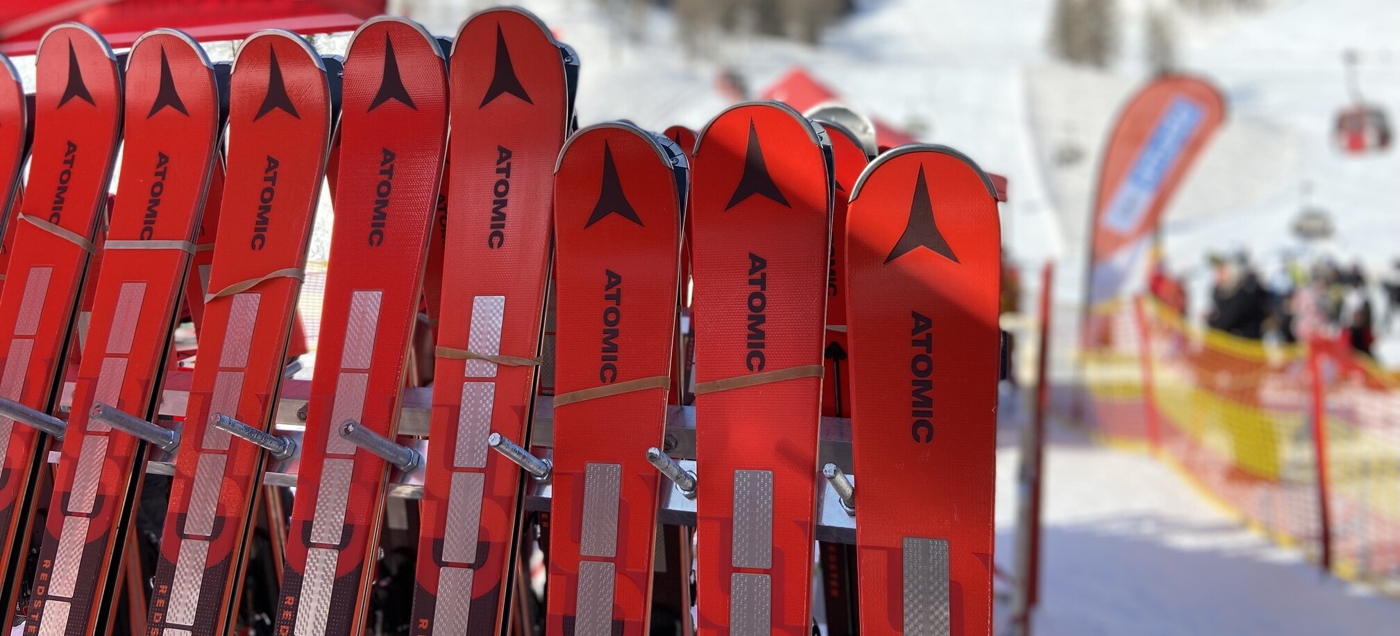 Red Atomic ski pairs leaning against a ski rack
