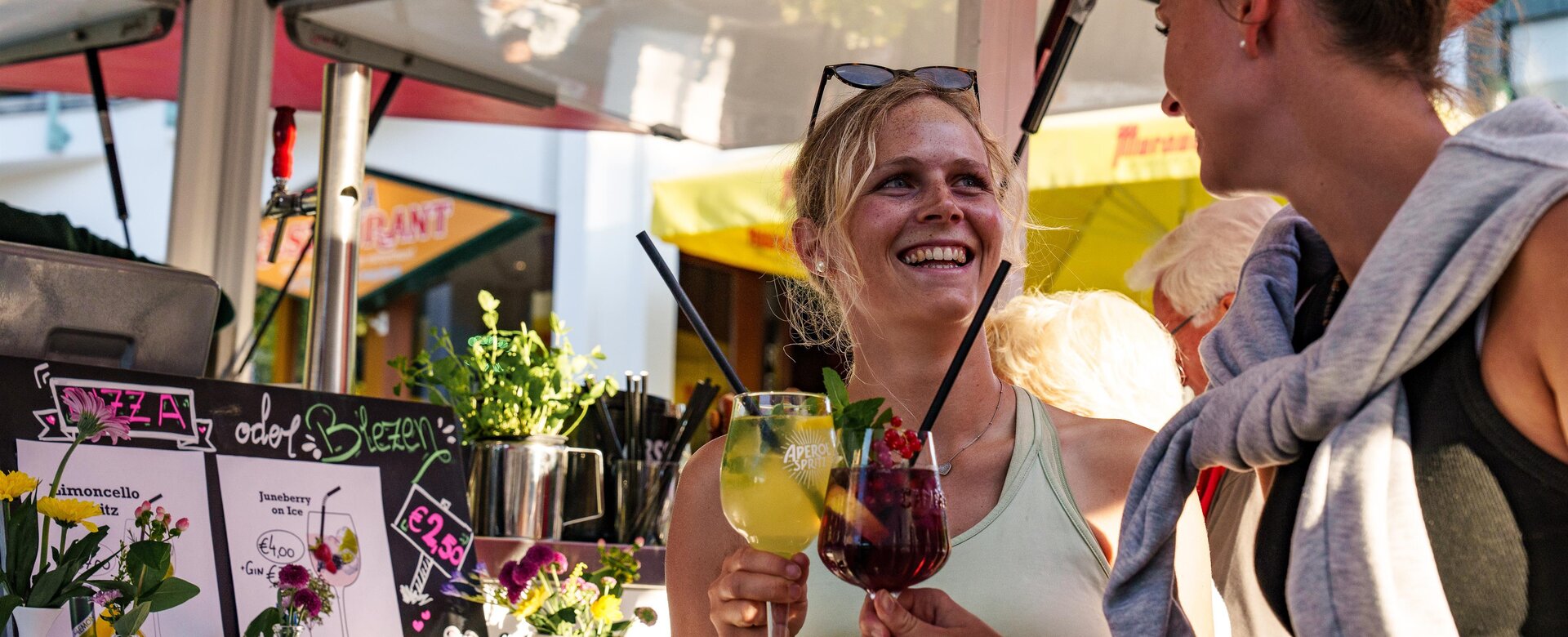 Zwei Frauen stoßen mit bunten Cocktails an einem Sommerstand an | © Flachau Tourismus