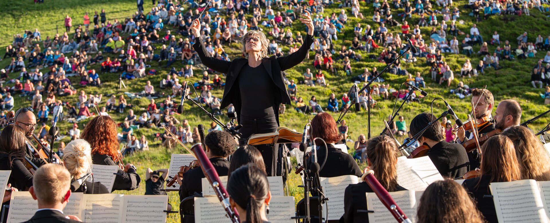 Dirigent steht vor dem Orchester und dahinter sitzen die Zuschauer auf einer Wiese | © Gasteinertal Tourismus GmbH, Fotoatelier Wolkersdorfer 