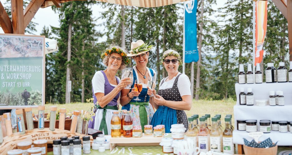 Drei Frauen in Dirndl mit Blumenkränzen präsentieren Kräuterprodukte beim Hochkönig-Kräuterfest. | © Miriam Lottes