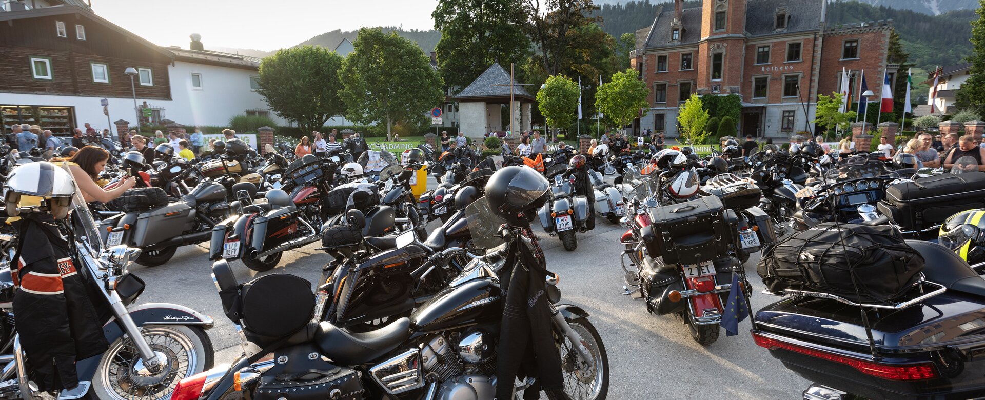 Dutzende Harley-Davidson-Motorräder und Biker auf zentralem Platz vor historischem Gebäude bei der Charity-Tour in den Alpen | © Harald Steiner