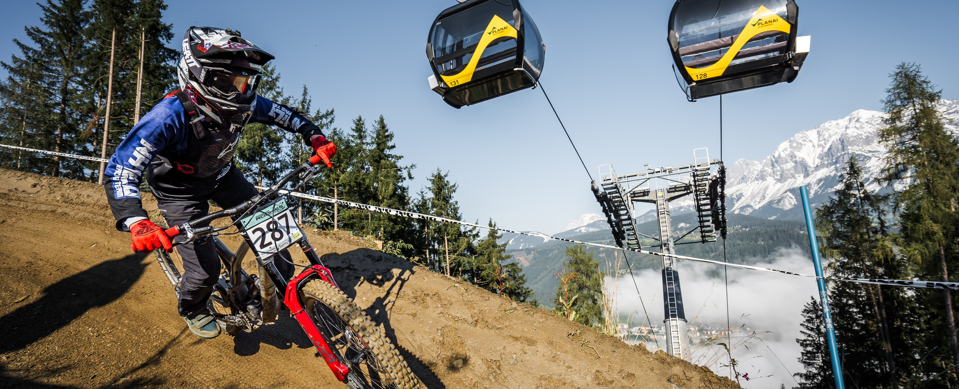 Mountainbiker mit Startnummer fährt bei Downhill-Rennen unter Gondelbahn an der Planai bergab | © Vladimir Stanescu