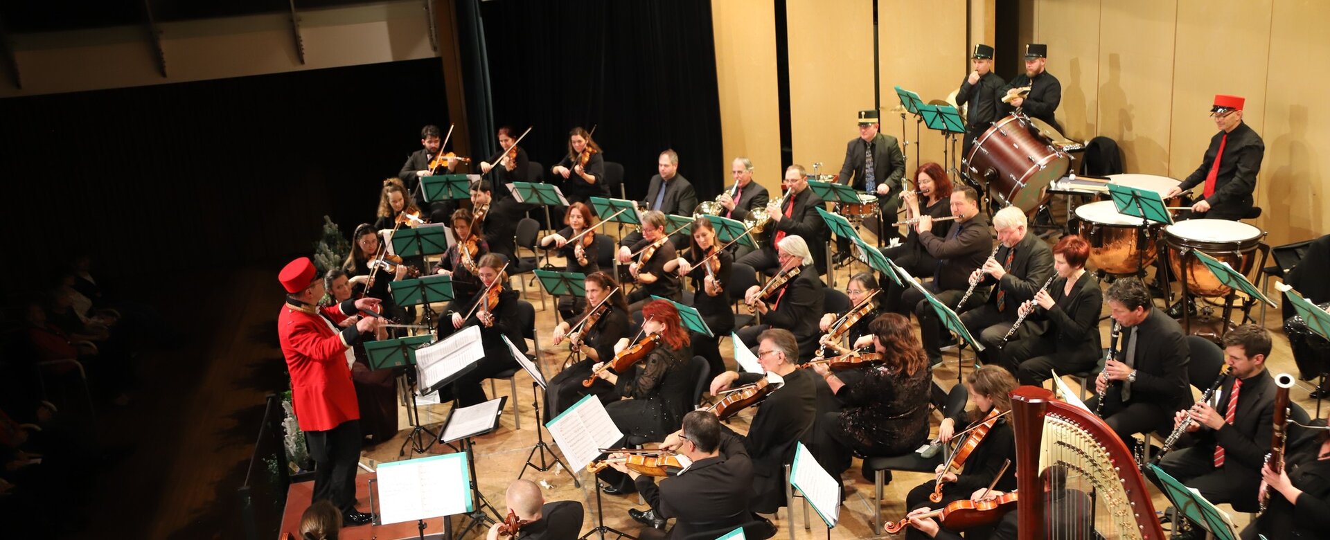 Großes Orchester mit Dirigent in rotem Frack bei Konzert der Sinfonietta St. Johann, viele Streich- und Blasinstrumente | © Jocongress