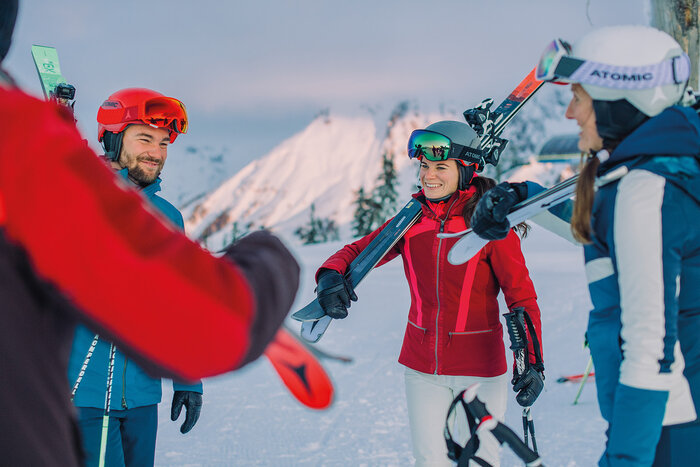 Skikurs Back2Ski – Wiedereinsteiger auf der Piste | © Ski amadé Eine Gruppe Skifahrer mit Skiern auf der Schulter tauscht sich aus – Teil des Back2Ski-Skikurses für Wiedereinsteiger. | © Ski amadé