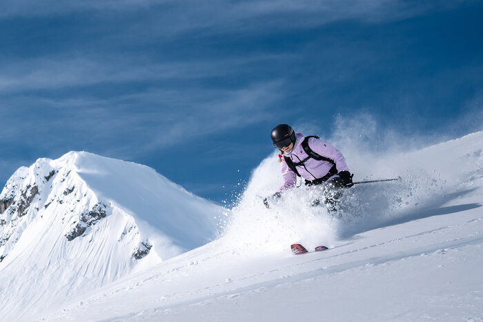 Tiefschnee-Genuss beim Freeriden in Zauchensee | © Liftgesellschaft Zauchensee/C.Schartner Skifahrerin mit Helm fährt im Tiefschnee hangabwärts, Pulverschnee spritzt bei Kurvenfahrt auf | © Liftgesellschaft Zauchensee/C.Schartner