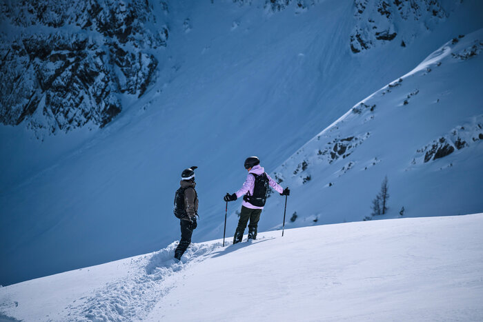 Freerider planen ihre Abfahrt im unberührten Zauchensee-Gelände | © Liftgesellschaft Zauchensee/C.Schartner Zwei Freerider mit Helmen stehen im Tiefschnee vor steilem Hang und besprechen ihre Abfahrtsroute | © Liftgesellschaft Zauchensee/C.Schartner