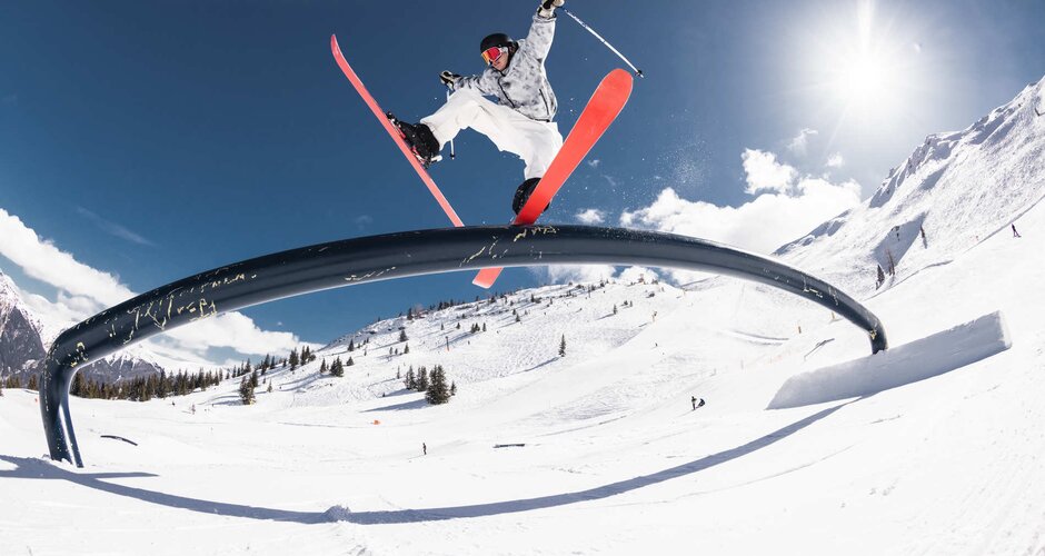 Skifahrer gleitet über eine Stange mit dem hinteren Teil der Skier und die vorderen Spitzen sind weit auseinander | © Q-Parks Hannes Mautner
