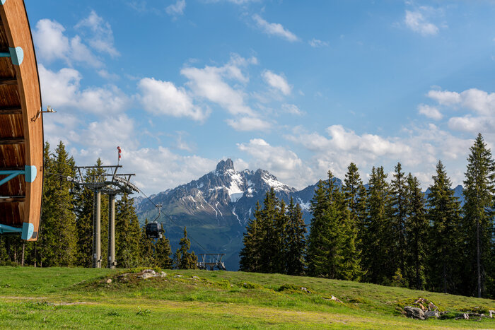 Papageno-Bahn mit Blick auf die Bischofsmütze bei Filzmoos | © Coen Weesjes Papageno-Gondel vor grüner Alm und dem markanten Doppelgipfel Bischofsmütze bei Filzmoos | © Coen Weesjes
