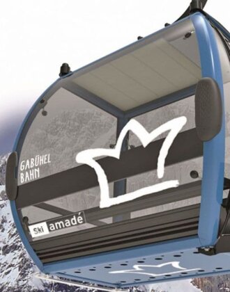Blau-schwarze Gabühel-Gondel mit Hochkönig-Logo vor schneebedeckter Felswand im Skigebiet Ski amadé | © Hochkönig Bergbahnen