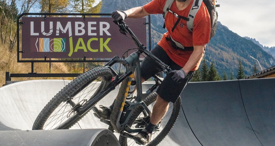 Ein Mountainbiker fährt mit Schwung über eine Welle am asphaltierten Pumptrack vor dem Lumberjack. | © Shuttleberg