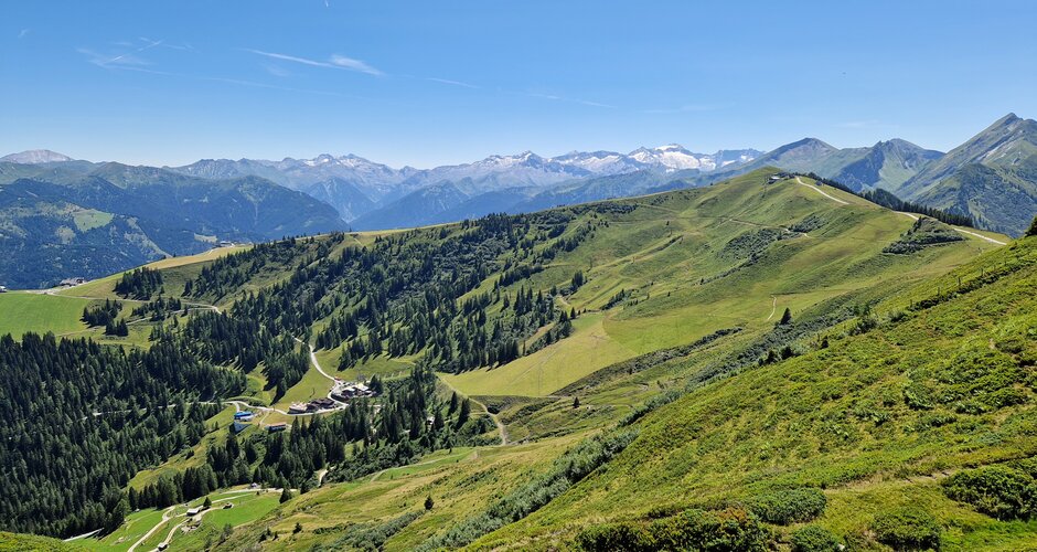 Blick vom Kreuzkogel auf grüne Bergrücken, Almwege und das weite Panorama der Hohen Tauern bei klarem Sommerhimmel. | © TVB Großarltal