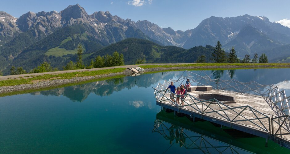 Familie auf Holzplattform am Prinzensee in Maria Alm, klares Wasser, Bergpanorama Hochkönig im Hintergrund | © Roland Haschka
