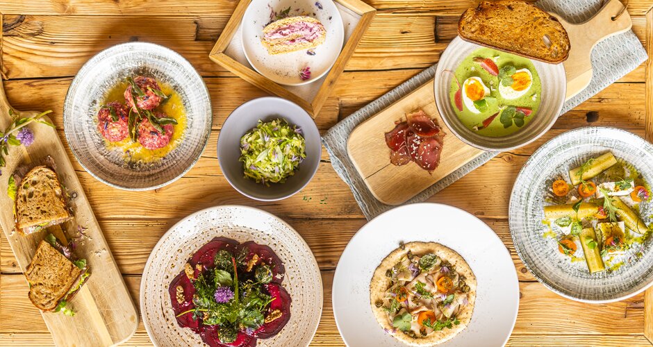 Mehrere angerichtete Speisen mit Brot, Suppe, Salat und Dessert liegen auf einem rustikalen Holztisch. | © Hochkönig Tourismus GmbH