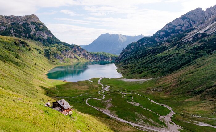 Bergsee in Wagrain-Kleinarl mit Alm und Wasserläufen | © Wagrain-Kleinarl Tourismus Blick auf einen klaren Bergsee mit Alm, Wiesen und Wasserläufen in einem von Bergen eingerahmten Hochtal | © Wagrain-Kleinarl Tourismus