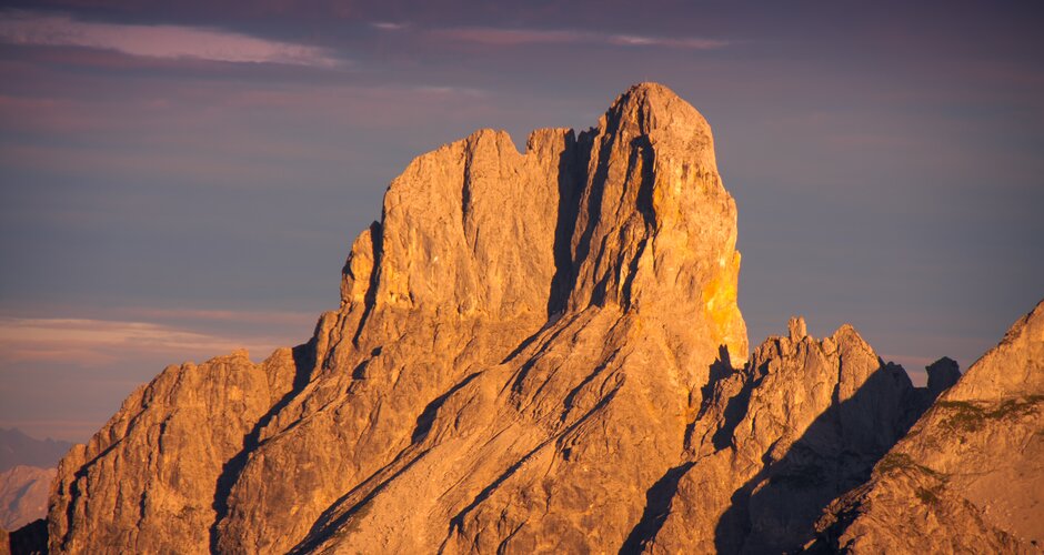 Die Bischofsmütze im Dachsteingebirge wird bei Sonnenuntergang in warmes, goldenes Licht getaucht – markante Felssilhouette | © CoenWeesjes