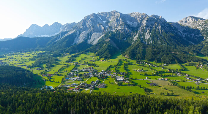 View of the green Ramsau plateau with Dachstein backdrop | © Herbert Raffalt Aerial view of the Ramsau plateau with wide green meadows, scattered houses and the mighty Dachstein mountain backdrop | © Herbert Raffalt