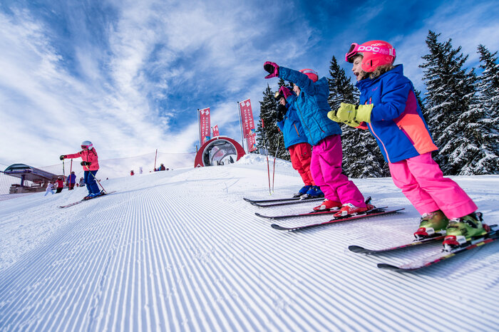 Ski amadé Minis Week – kids at the start line Kids in colorful ski outfits stand at the start of a race slope, eagerly waiting for the start signal to ski down.