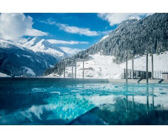 Schwimmbecken mit bergiger Schneelandschaft im Hintergrund | © Max Steinbauer Photography