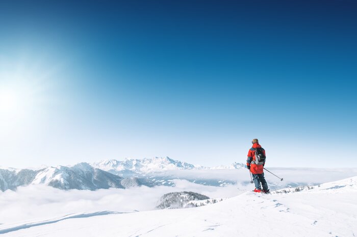Allein auf der Piste mit Weitblick in Ski amadé Ein Skifahrer steht allein auf der Piste und blickt ins weite, nebelverhangene Tal