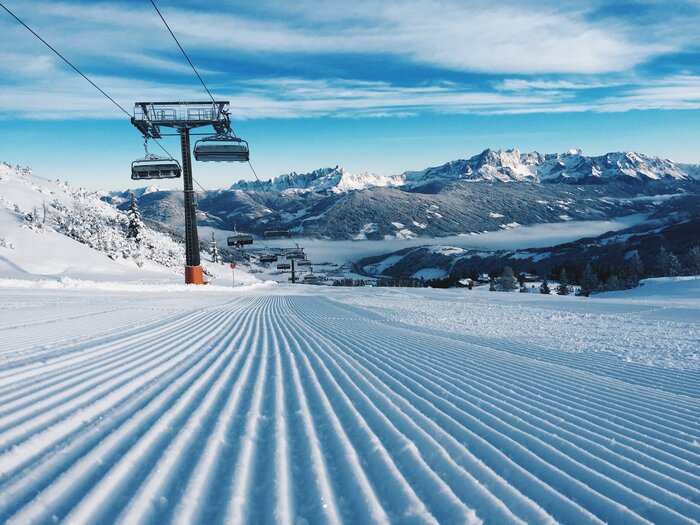 Moderne Liftanlagen und perfekte Pisten in Ski amadé | © Ski amadé Frisch präparierte Piste mit Sessellift und schneebedeckten Bergen. | © Ski amadé