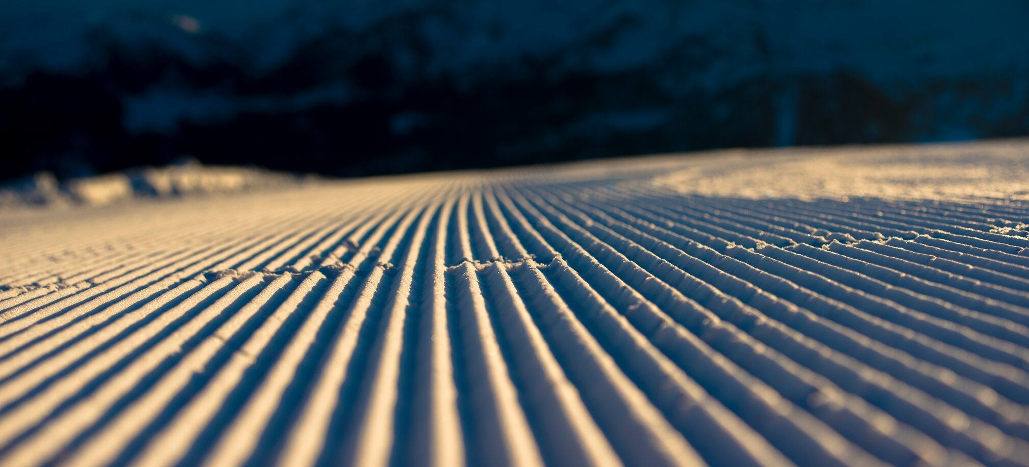 Close-up of a perfectly groomed ski slope at morning light with mountains in the background. | © Ski amadé
