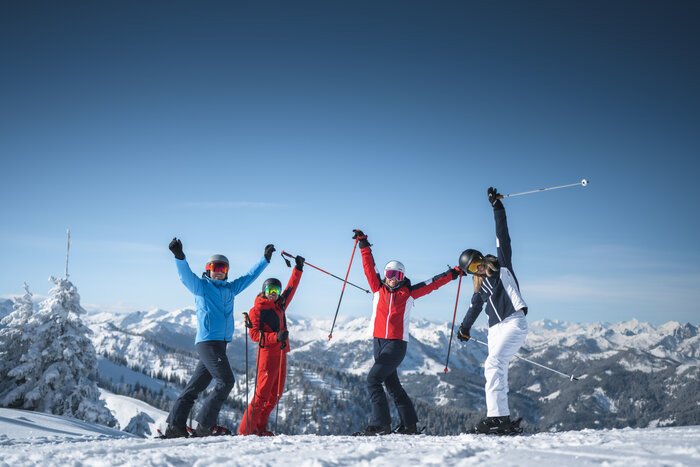 Skispaß hoch vier | © Ski amadé Vier Freunde in Skiausrüstung stehen auf der Piste und Strecken die Arme freudvoll in die Höhe. | © Ski amadé