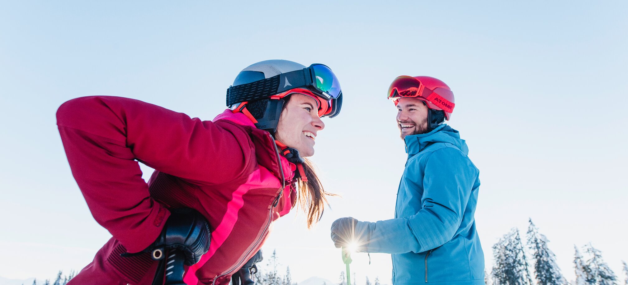 Eine Skifahrerin lacht und beugt sich vor, ein Skifahrer schaut sie an. | © Ski amadé