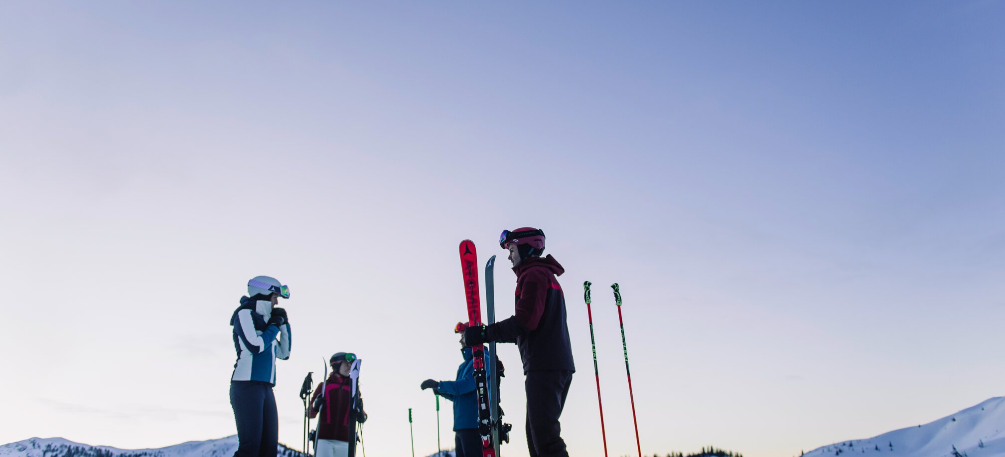 Four skiers stand on a snowy slope under a violet sky. | © Ski amadé