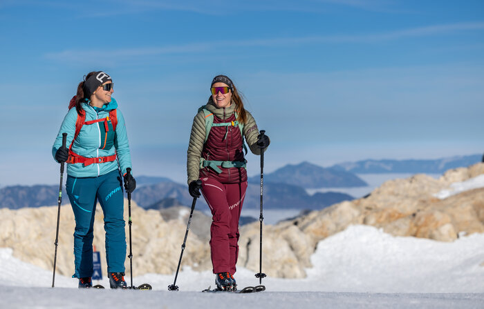 Große Mitterstein-Tour bei Sonnenschein | © Harald Steiner Zwei Frauen gehen mit Skitourenausrüstung und Stöcken durch sonnige Schneelandschaft | © Harald Steiner