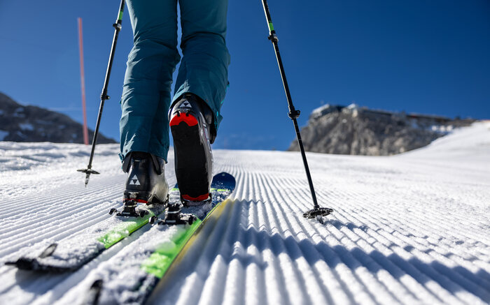 Kleine Mitterstein-Tour – Detail beim Aufstieg auf der Piste | © Harald Steiner Nahaufnahme eines Tourenskischuhs auf gespurer Piste mit Stöcken und Sonne im Hintergrund | © Harald Steiner