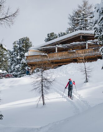 Skitourengeher nähert sich auf verschneitem Hang der Graukogelhütte durch den Wald | © Gasteinertal Tourismus GmbH, Christoph Oberschneider