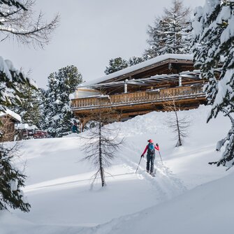 Skitourengeher nähert sich auf verschneitem Hang der Graukogelhütte durch den Wald | © Gasteinertal Tourismus GmbH, Christoph Oberschneider