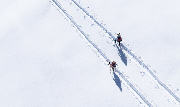 Pistentourengeher auf der Planai bei sonnigem Wintertag | © Josh Absenger Zwei Pistentourengeher mit Stöcken auf verschneiter Spur bei Sonne auf der Planai unterwegs | © Josh Absenger
