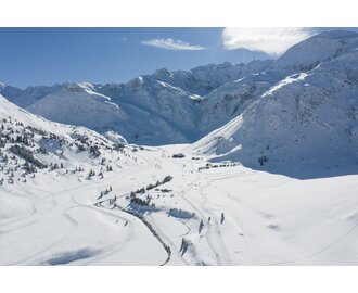 Weitläufige Langlaufloipen schlängeln sich durch das verschneite Tal von Sportgastein, umgeben von hohen Berggipfeln. | © Gasteinertal Tourismus GmbH, Christoph Oberschneider