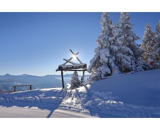 Wooden Naturplatzl gate in Grossarltal ski area beside snow covered trees with groomed slope and mountain view | © Tourismusverband Grossarltal