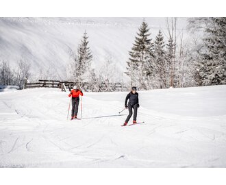 Zwei Langläufer auf präparierter Loipe im Großarltal mit verschneiten Wiesen, Bäumen und Winterlandschaft | © Gipfelfieber