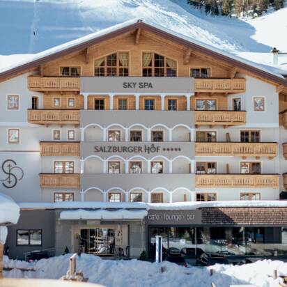 Hotel Salzburger Hof mit Holzfassade vor verschneiter Piste und Skilift | © Nadia Jabli