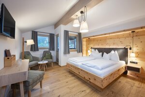 Helles Doppelzimmer mit Holzbett, Sitzecke, TV, Schreibtisch und großen Fenstern