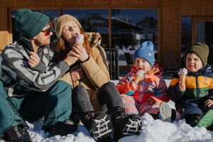 Zwei Erwachsene und zwei Kinder essen Eis im Schnee in Winterkleidung