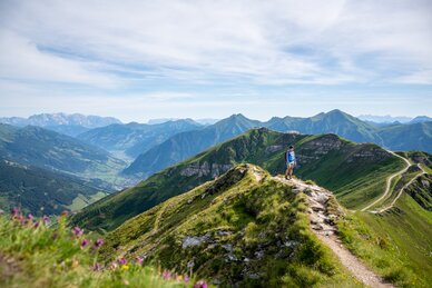 Hiker on a ridge trail at Stubnerkogel with a wide view over the green Gastein Valley and the surrounding mountain peaks | © Gasteinertal Tourismus GmbH, Christoph Oberschneider