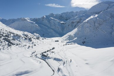 Weitläufige Langlaufloipen schlängeln sich durch das verschneite Tal von Sportgastein, umgeben von hohen Berggipfeln. | © Gasteinertal Tourismus GmbH, Christoph Oberschneider