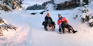 Eltern mit Kindern beim gemeinsamen Rodeln im Winterurlaub in Gastein | © GTG