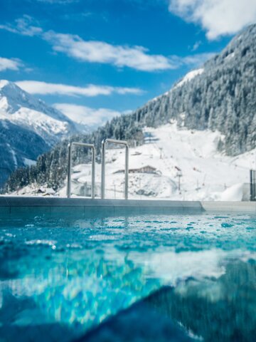 Schwimmbecken mit bergiger Schneelandschaft im Hintergrund | © Max Steinbauer Photography