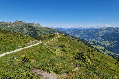 Panoramic hiking trail over green mountain ridges with valley view and blue sky, along the Himmelsroute near Kieserl. | © TVB Großarltal