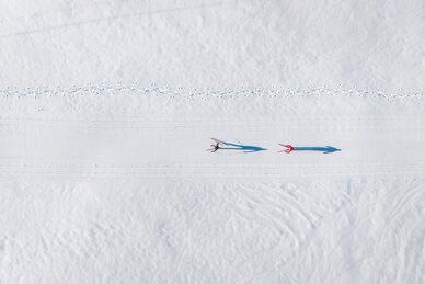 Two cross-country skiers glide along groomed trail in Grossarltal across wide snowy winter landscape | © Gipfelfieber